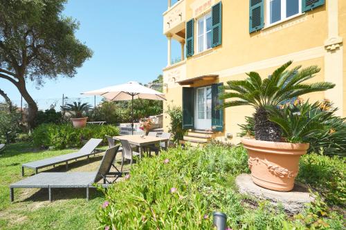 a patio with a table and benches and an umbrella at Villa Margherita in Levanto