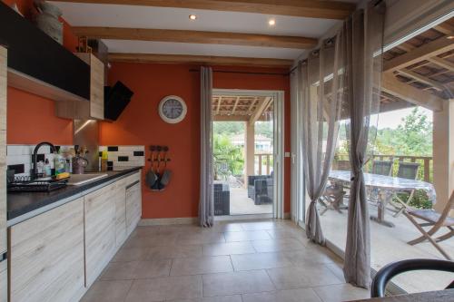 an open kitchen with orange walls and a patio at Villa La Fenière in Payzac