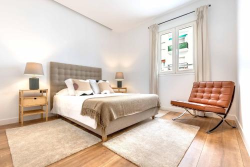 a bedroom with a bed and a chair and a window at Luces en Madrid in Madrid