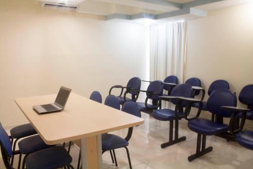 a room with a table and chairs with a laptop on it at Hotel Agua Marinha in Natal