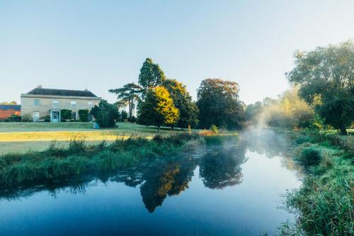 a view of a river with a house in the background at West Lexham Retreat in Kings Lynn