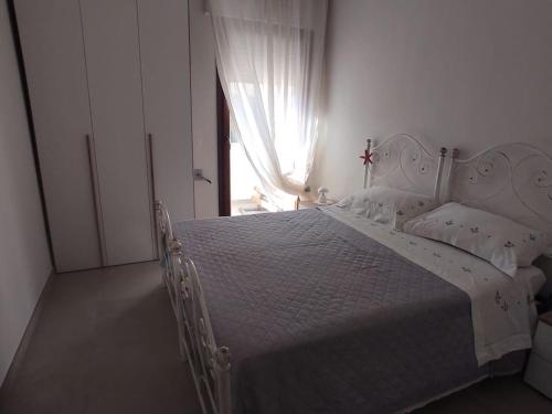 a white bed in a white bedroom with a window at a CASA DI PAPY in Lido Conchiglie