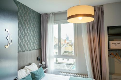 a bedroom with a bed and a large window at Hôtel Central in Poitiers