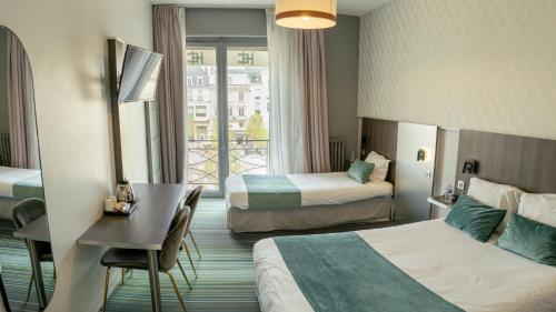a hotel room with two beds and a desk at Hôtel Central in Poitiers
