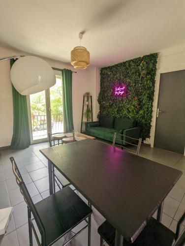 - un salon avec une table et un mur vert dans l'établissement La jungle urbaine avec garage privé & climatisation, à Perpignan