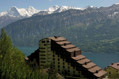a building on the side of a lake with mountains at Dorint Blüemlisalp Beatenberg/Interlaken in Beatenberg