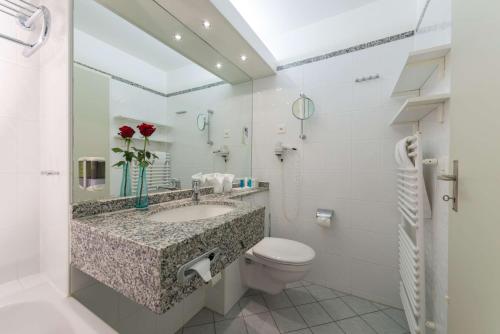 a bathroom with a sink and a toilet at Dorint Blüemlisalp Beatenberg/Interlaken in Beatenberg