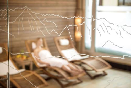 a woman sitting in a chair with a book and a graph at Dorint Blüemlisalp Beatenberg/Interlaken in Beatenberg