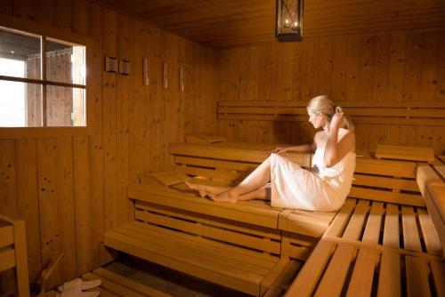 a woman sitting in a sauna talking on a cell phone at Dorint Blüemlisalp Beatenberg/Interlaken in Beatenberg