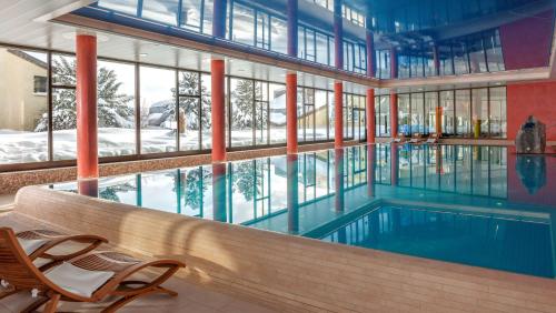 a swimming pool in a building with a large window at Dorint Blüemlisalp Beatenberg/Interlaken in Beatenberg