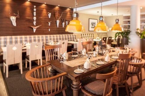 a restaurant with a long wooden table and chairs at Dorint Blüemlisalp Beatenberg/Interlaken in Beatenberg