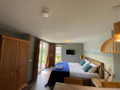 a bedroom with a bed and a table and a tv at Recreatiepark Wiringherlant in Hippolytushoef
