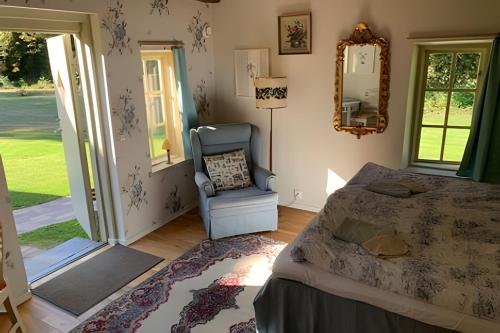 1 dormitorio con cama, silla y espejo en Vingårdens Bed & Breakfast, en Helsingborg