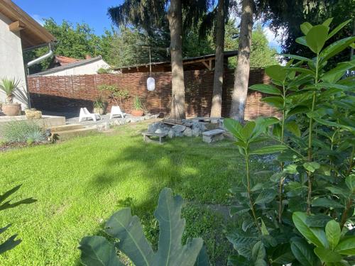 a backyard with a lawn with two chairs and trees at Marika Vendégház in Szigetmonostor