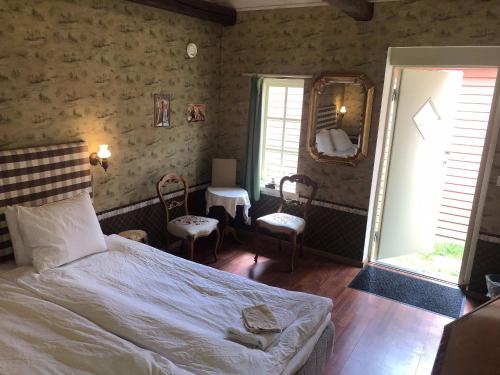a bedroom with a bed and two chairs and a mirror at Vingårdens Bed & Breakfast in Helsingborg