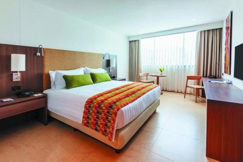 a hotel room with a large bed and a desk at Estelar Villavicencio Hotel & Centro De Convenciones in Villavicencio