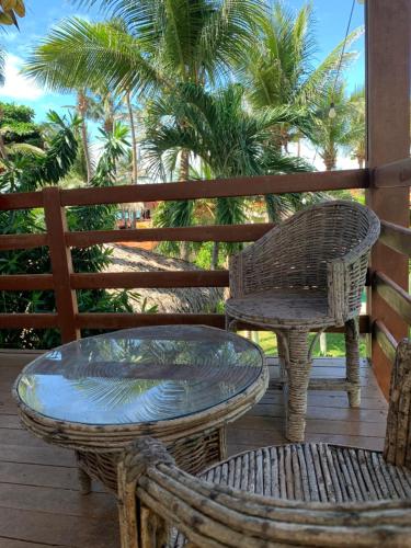 a table and chairs on a porch with palm trees at Ville Sweet Home in Canoa Quebrada
