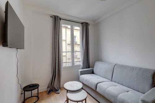 un salon avec un canapé et une télévision dans l'établissement 566-Suite Courcelles - Superbe Appartement à Paris, à Paris