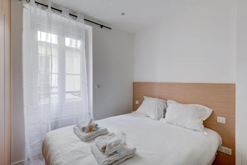 une chambre avec deux lits avec des draps blancs et une fenêtre dans l'établissement 566-Suite Courcelles - Superbe Appartement à Paris, à Paris