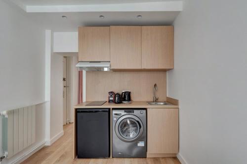 une cuisine avec une machine à laver et un évier dans l'établissement 566-Suite Courcelles - Superbe Appartement à Paris, à Paris