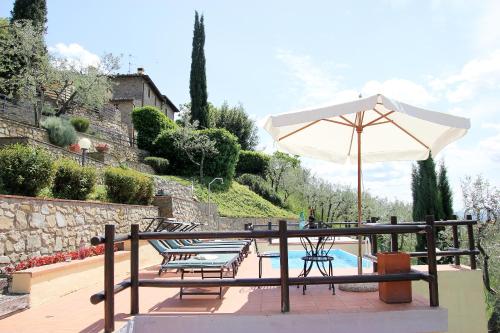 a patio with a table and an umbrella next to a pool at Tuscany Villa Chianti Hills - Villa Oliveta in Loro Ciuffenna