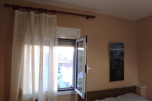 a bedroom with a window with white curtains at Happy Home in Agia Triada