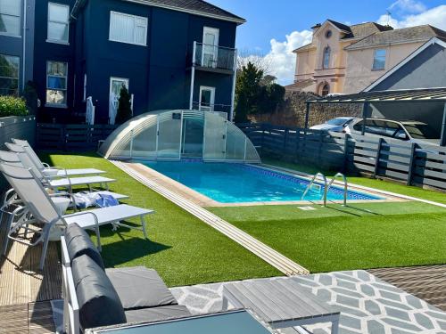 een achtertuin met een zwembad en een huis bij Atlantis Holiday Apartments in Torquay