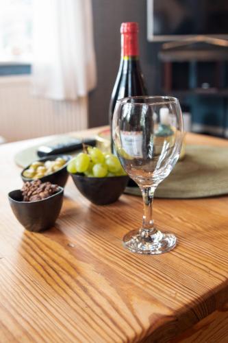 a wine glass sitting on a wooden table with bowls of grapes at Holiday Home Itzendorfer Rott-2 by Interhome in Norddeich