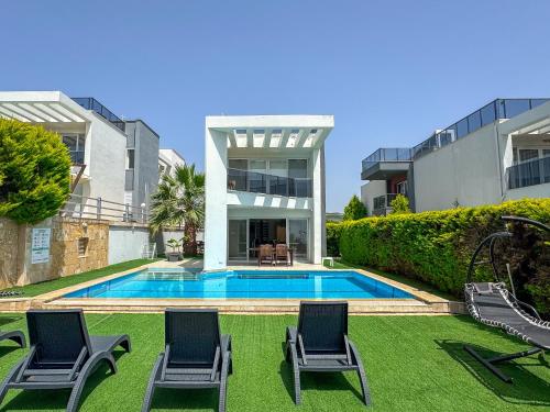 a house with a swimming pool and two lawn chairs at Exclusive Villas in Kusadası