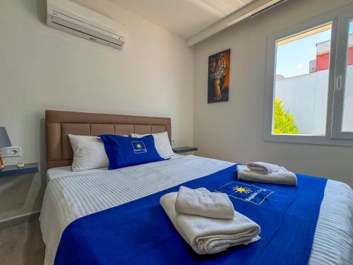 a bedroom with a blue bed with towels on it at Exclusive Villas in Kusadası