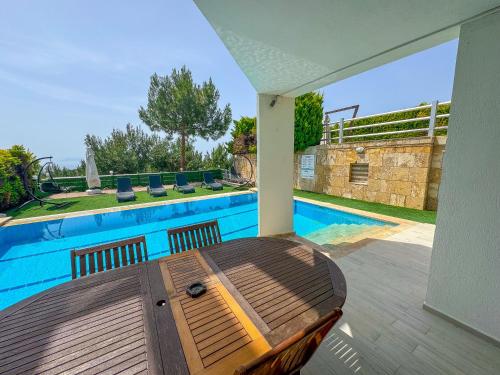 a patio with a wooden table next to a swimming pool at Exclusive Villas in Kusadası