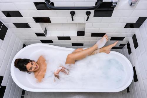 Apto Londrina Flat Hotel jacuzzi 43 m2 في لوندرينا: امرأة مستلقية في حوض الاستحمام