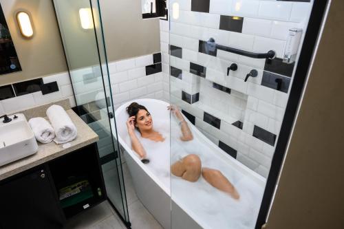 a woman laying in a bath tub in a bathroom at Apto Londrina Flat Hotel jacuzzi 43 m2 in Londrina