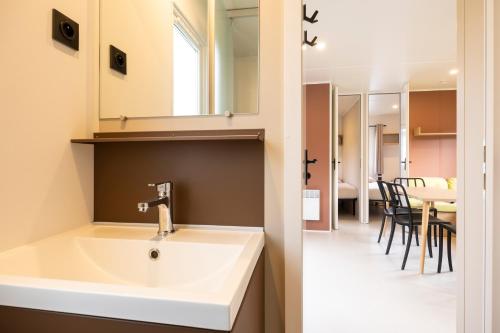 a bathroom with a sink and a dining room at Verblijfpark Tulderheyde - Leisure only! in Poppel