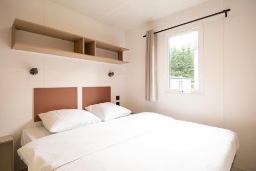 a bedroom with two white beds and a window at Verblijfpark Tulderheyde - Leisure only! in Poppel