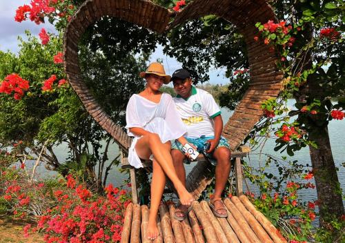 a man and woman sitting on a bench with a heart at Laguna Rosa Glamping in Coveñas
