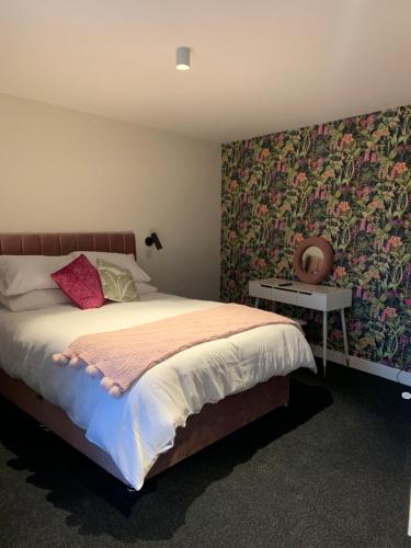 a bedroom with a large bed with floral wallpaper at STAG & THISTLE HOTEL AND RESTAURANT in Fraserburgh