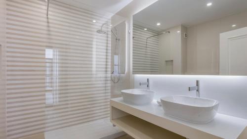 a white bathroom with two sinks and a shower at Pine Cliffs Village in Albufeira