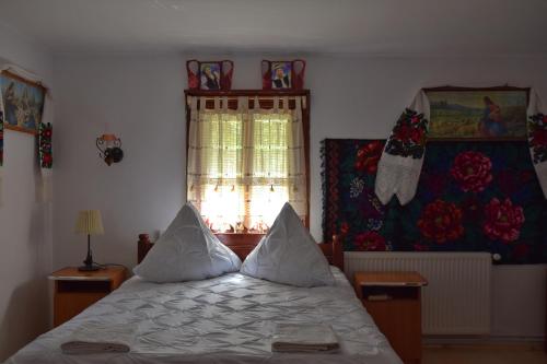 a bedroom with a bed with pillows and a window at Pensiunea Maramu in Breb