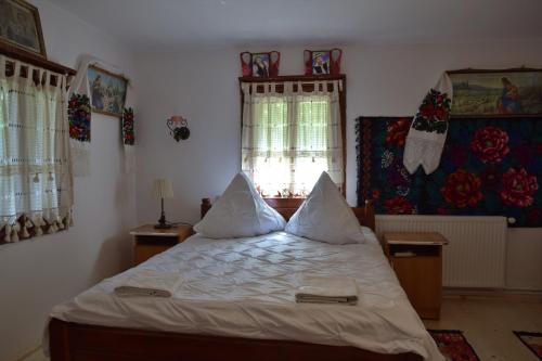 a bedroom with a bed with white sheets and pillows at Pensiunea Maramu in Breb