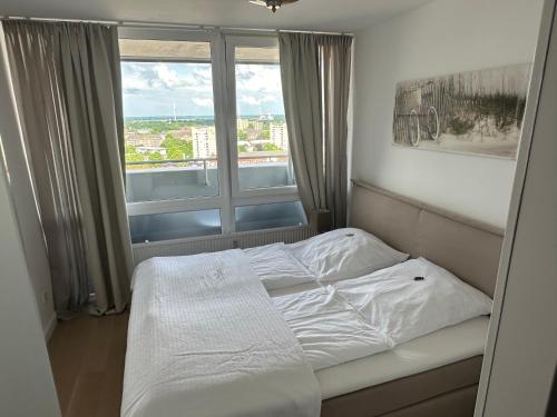 Bett in einem Zimmer mit einem großen Fenster in der Unterkunft Apartement Förde Blick in Bremerhaven
