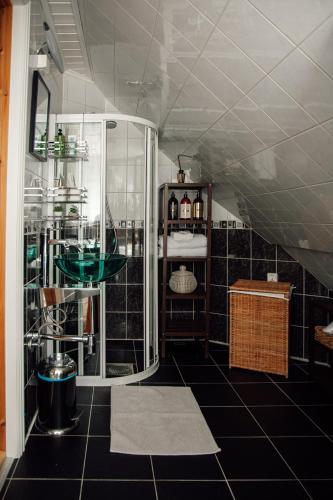 a bathroom with a glass shower and black tiles at Panorama Apartment with 360 view of the city Ålesund in Ålesund