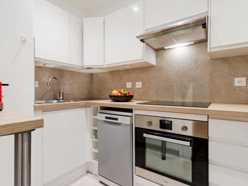 une cuisine avec des armoires blanches et un évier dans l'établissement Apartment La Commanderie by Interhome, à Deauville