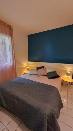 une chambre avec un grand lit avec un mur bleu dans l'établissement Cottage paisible au coeur du golf saint Laurent , linge de maison et ménage inclus, à Ploemel
