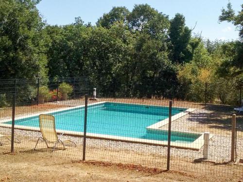 a swimming pool behind a fence with two chairs at Holiday Home Le Champ du Lac by Interhome in Salviac