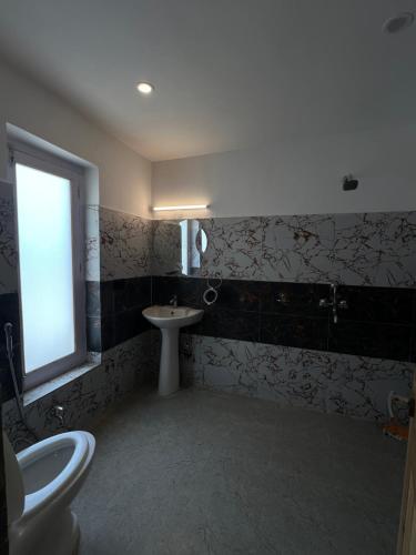 a bathroom with a toilet and a sink and a window at De katong in Leh