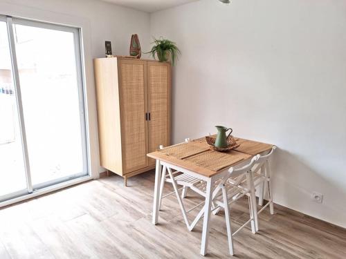 une table et des chaises dans une pièce avec un réfrigérateur dans l'établissement Studio rénové avec terrasse 40 m 2, à Palavas-les-Flots