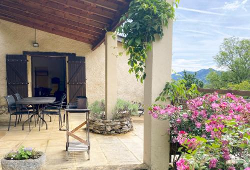 eine Terrasse mit einem Tisch, Stühlen und Blumen in der Unterkunft Gite de Serrelongue in Montségur