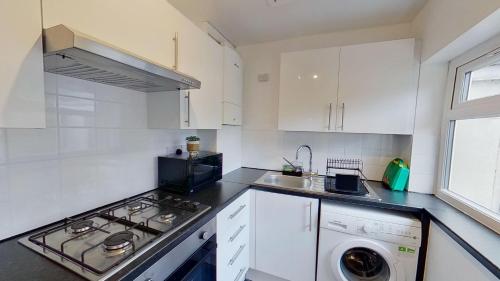 a white kitchen with a stove and a sink at Elegant 2 Bed House Near City Centre in Manchester