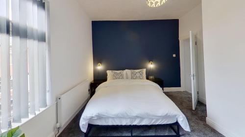 a bedroom with a large bed with a blue wall at Elegant 2 Bed House Near City Centre in Manchester